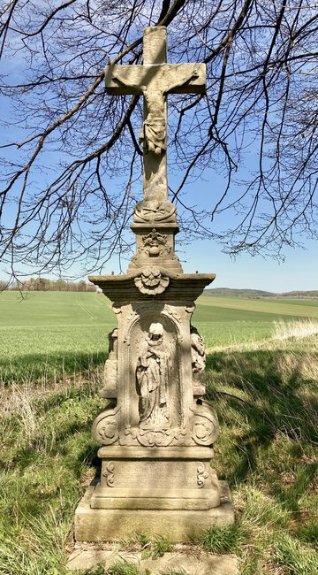 Bohatě zdobený poničený kříž v polích u Božanova